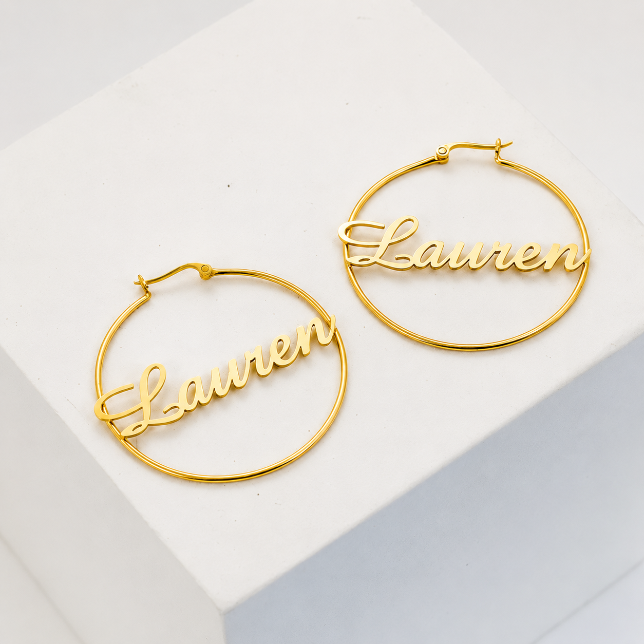 Gold hoop earrings with 'Lauren' engraving on a white background