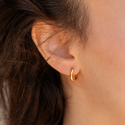 Close-up of a person wearing a gold hoop earring with dark hair and leather jacket.
