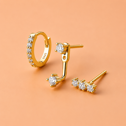 Gold hoop and stud earrings on a peach background