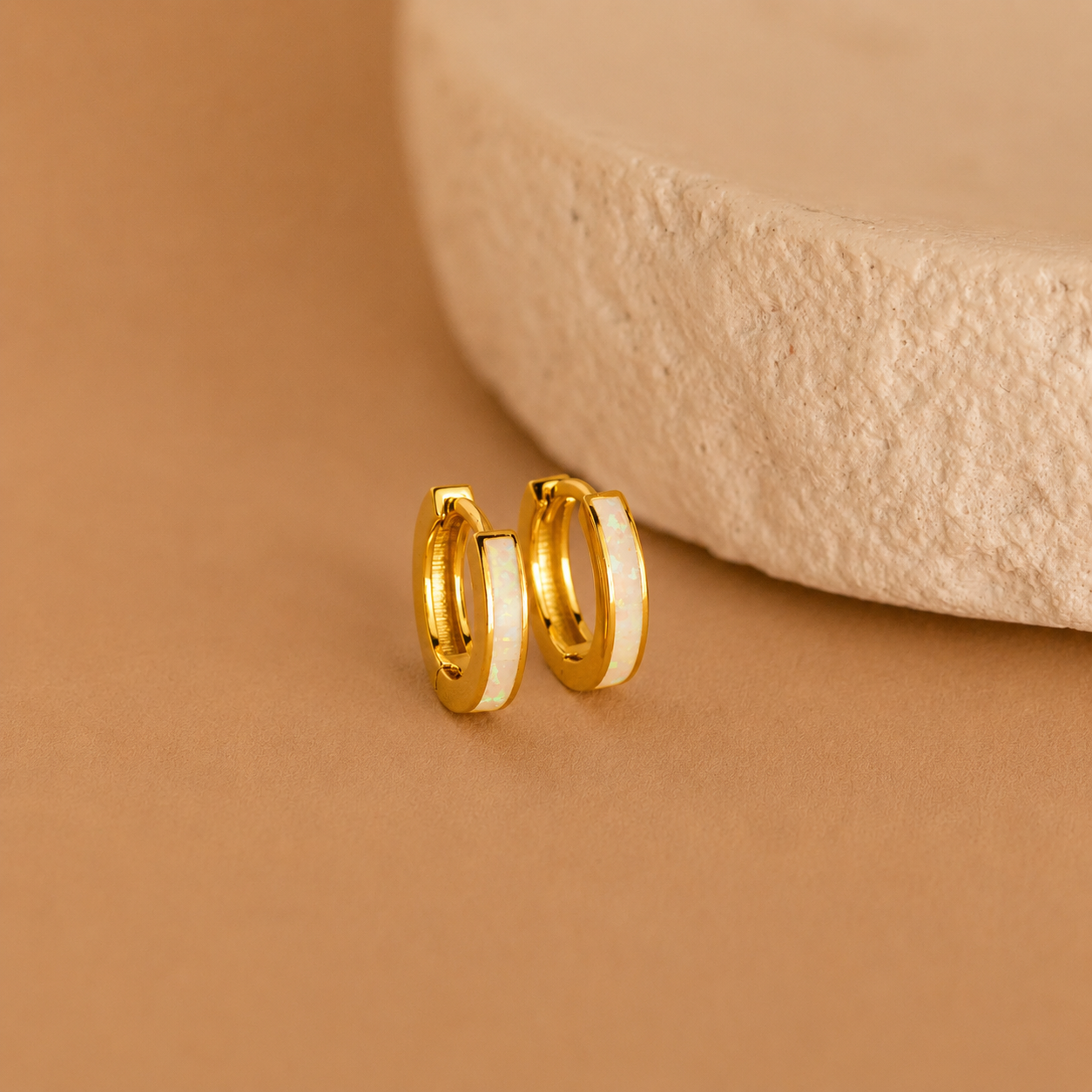 Gold hoop earrings on a beige background