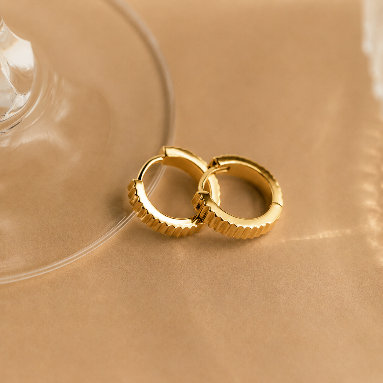 Pair of gold hoop earrings on a beige surface