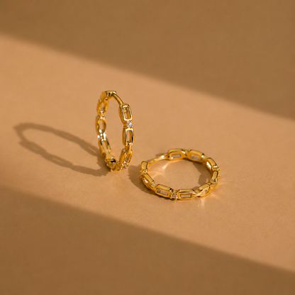 Two gold chain-link rings on a beige background