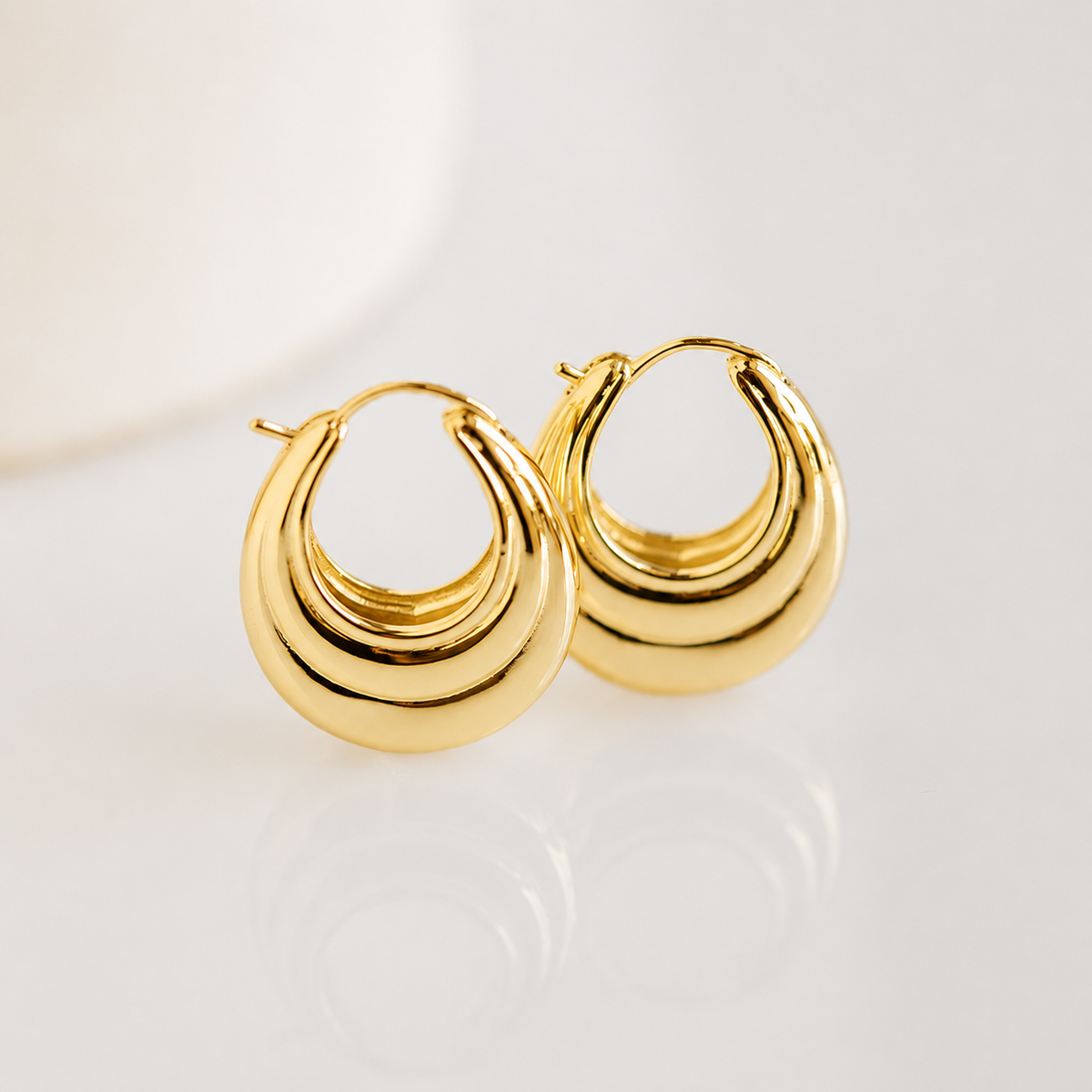 Gold hoop earrings on a light background
