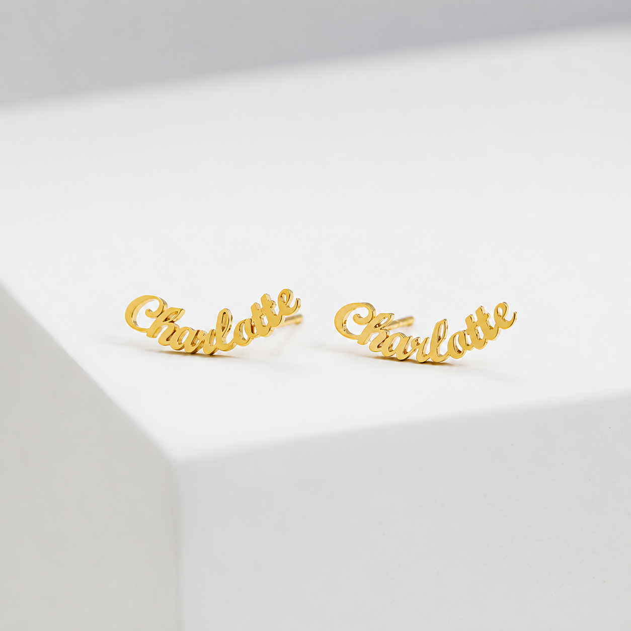 Gold 'Charlotte' earrings on a light gray background