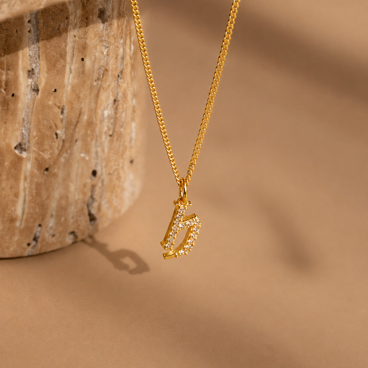 Gold necklace with a unique pendant on a beige background