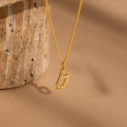 Gold necklace with a unique pendant on a beige background