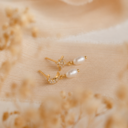 Pair of gold earrings with pearls on a beige fabric background