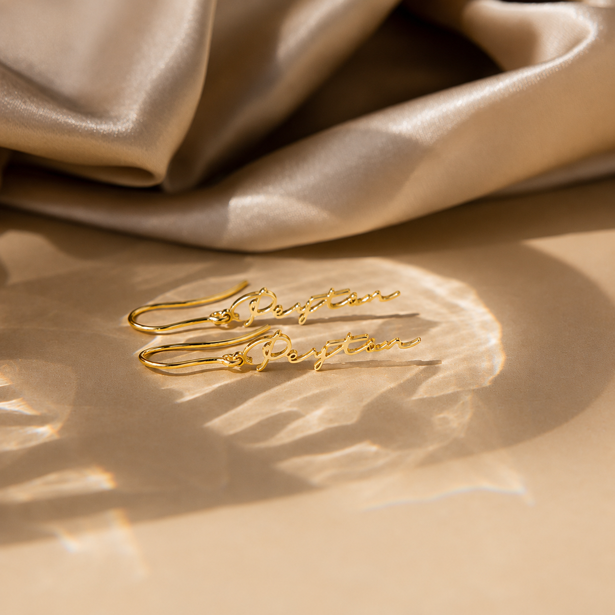 Gold earrings on a beige fabric background