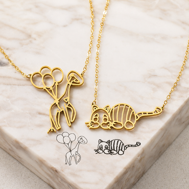 Gold necklaces with cat-shaped pendants on a marble surface