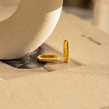 Two gold rings on a textured surface with a neutral background