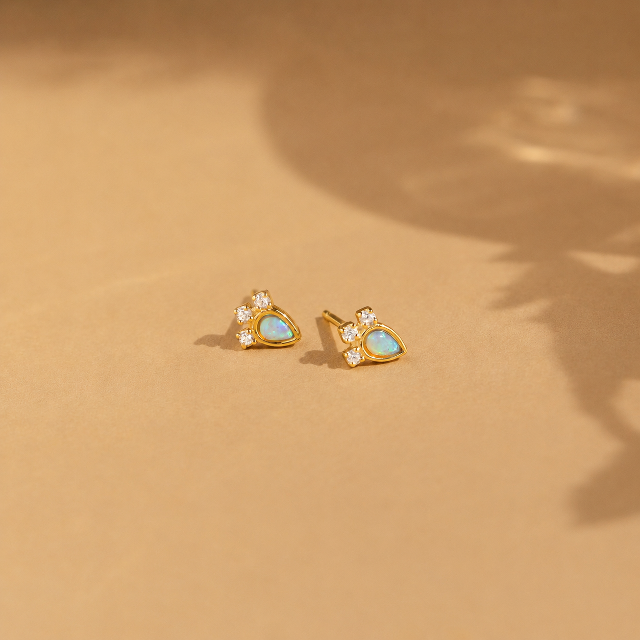 Gold earrings with opal stones on a beige background