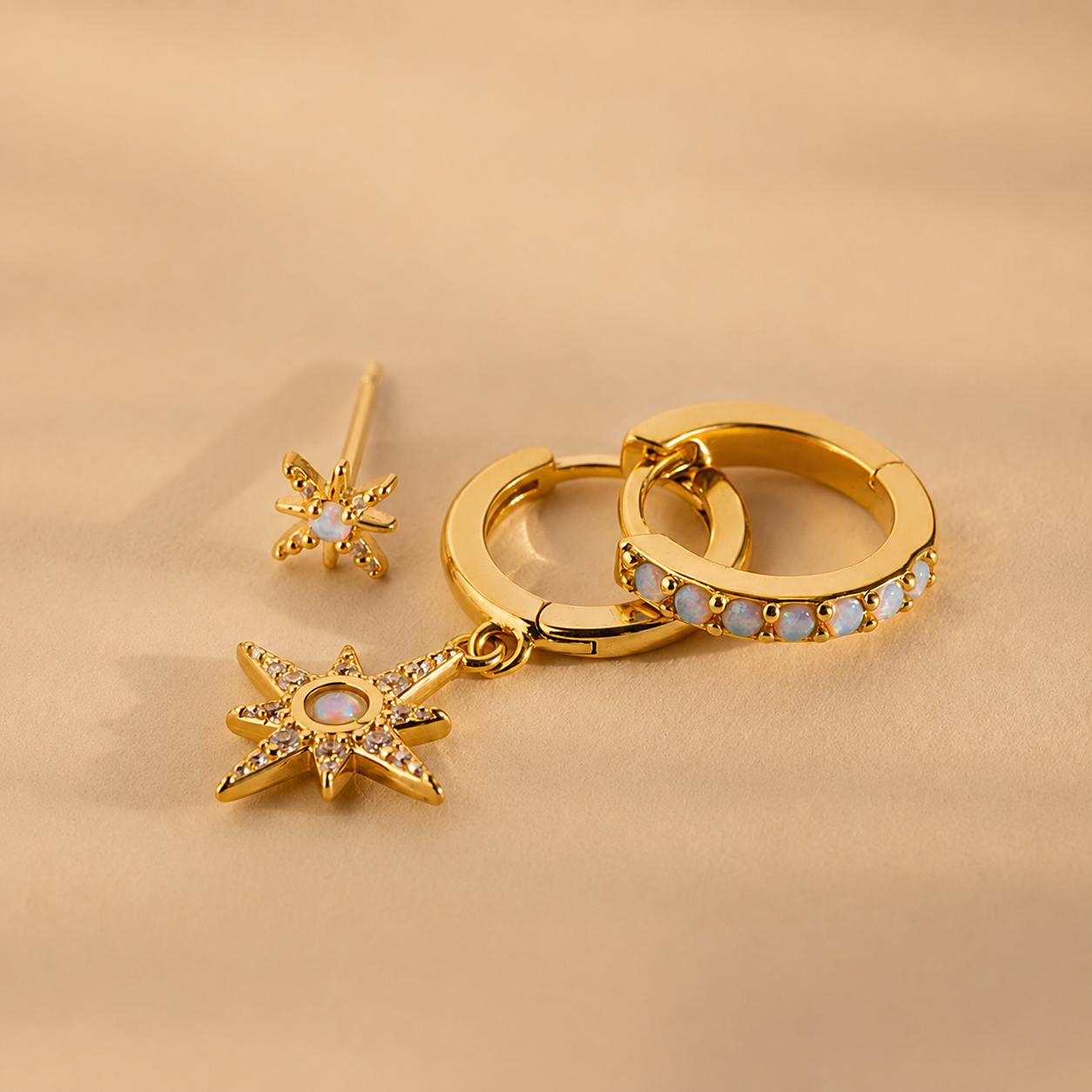 Gold hoop earrings with star-shaped charms on a beige background