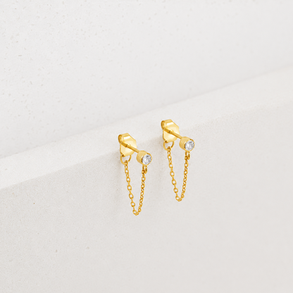 Gold chain earrings with small diamonds on a light gray background
