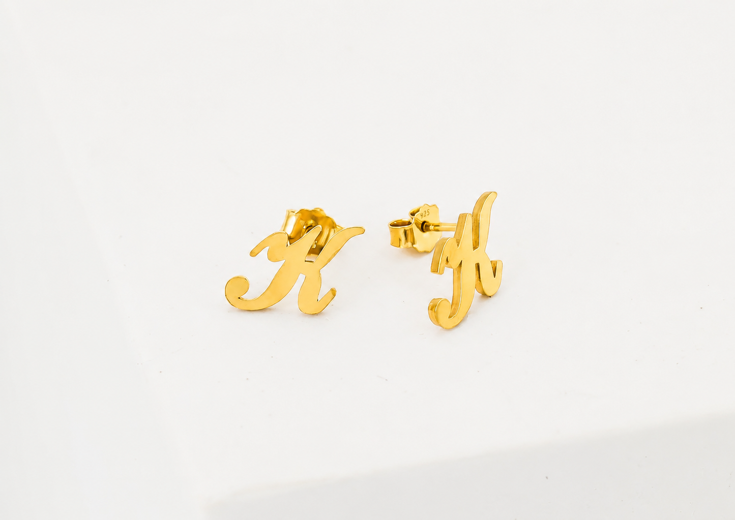 Gold letter 'H' earrings on a white background
