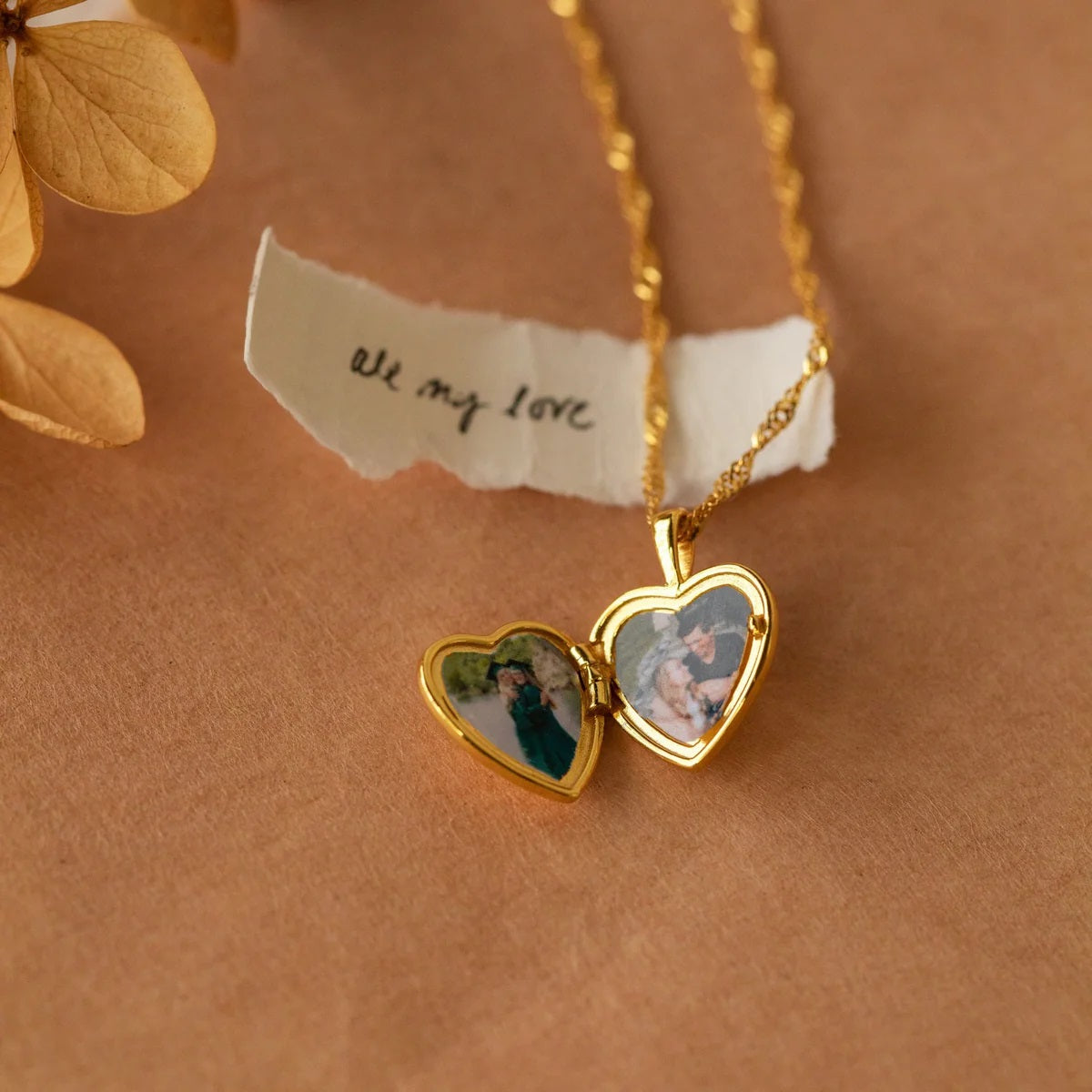 Gold heart-shaped locket with photos on a brown background with 'all my love' note.