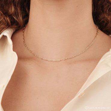 A close-up image of a dainty link chain necklace made of solid 925 sterling silver, displayed on a person's neck.