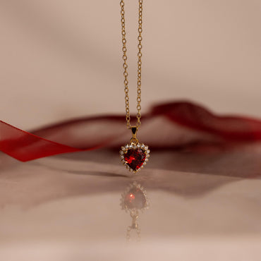Close-up of a sparkling heart-shaped garnet pendant surrounded by pave-set stones.