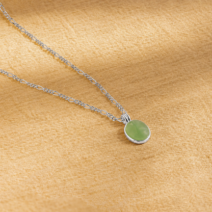 Necklace with a green pendant on a beige fabric background