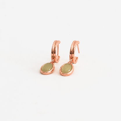 Rose gold hoop earrings with green stones on a white background