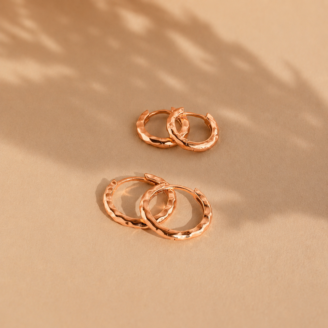 Rose gold hoop earrings on a beige background