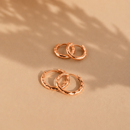Rose gold hoop earrings on a beige background