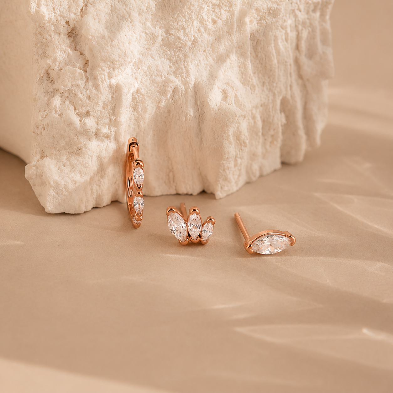 Rose gold earrings on a textured beige surface