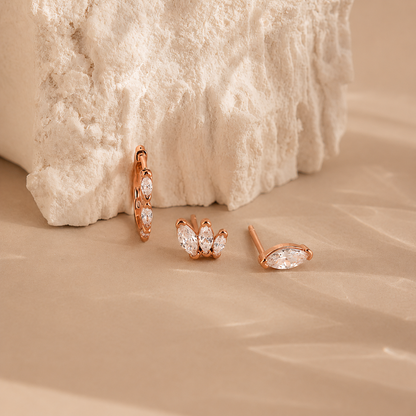 Rose gold earrings on a textured beige surface