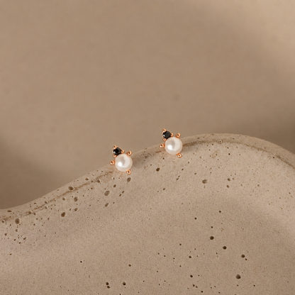 Pair of pearl earrings on a textured beige surface with a neutral background