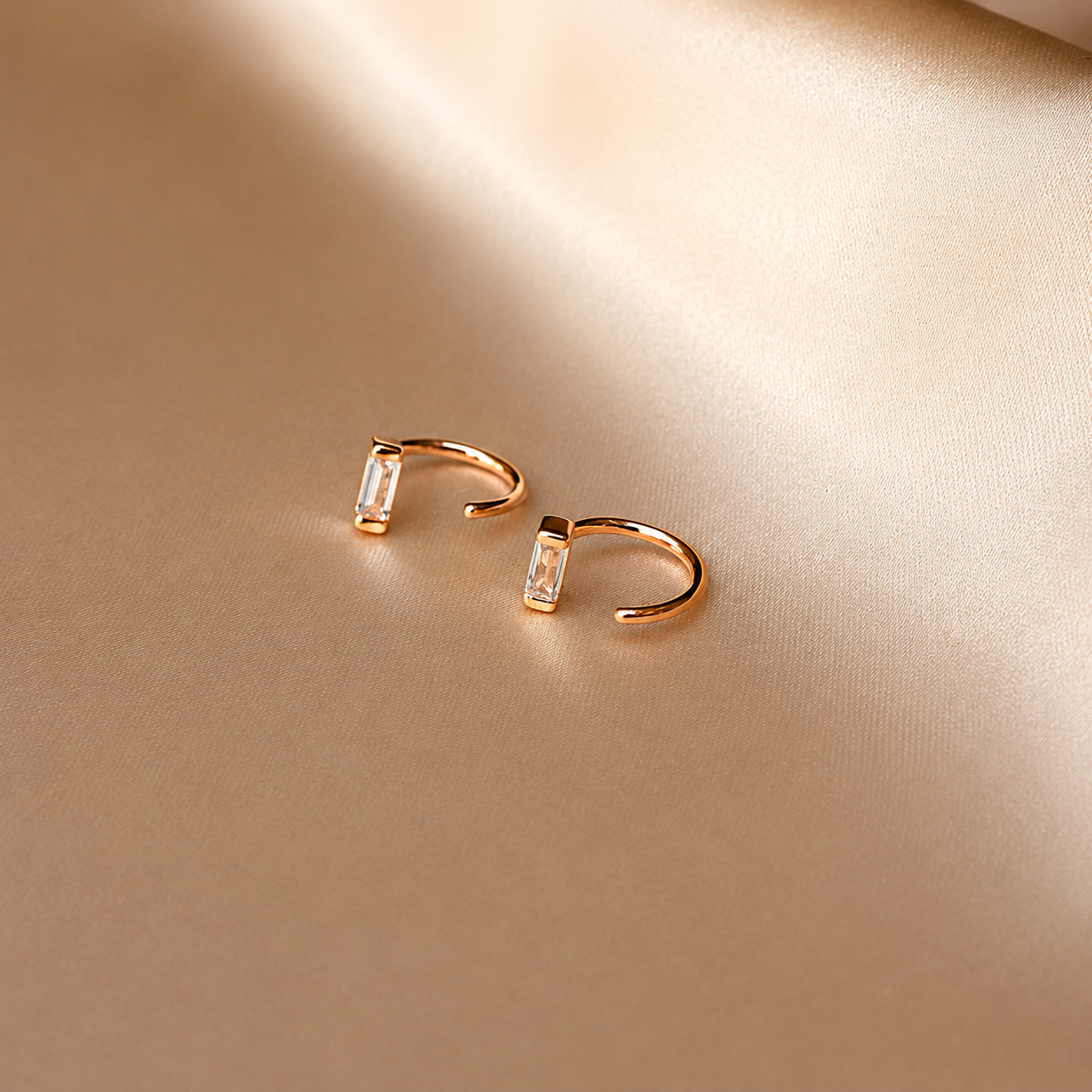 Gold hoop earrings with embedded stones on a beige background