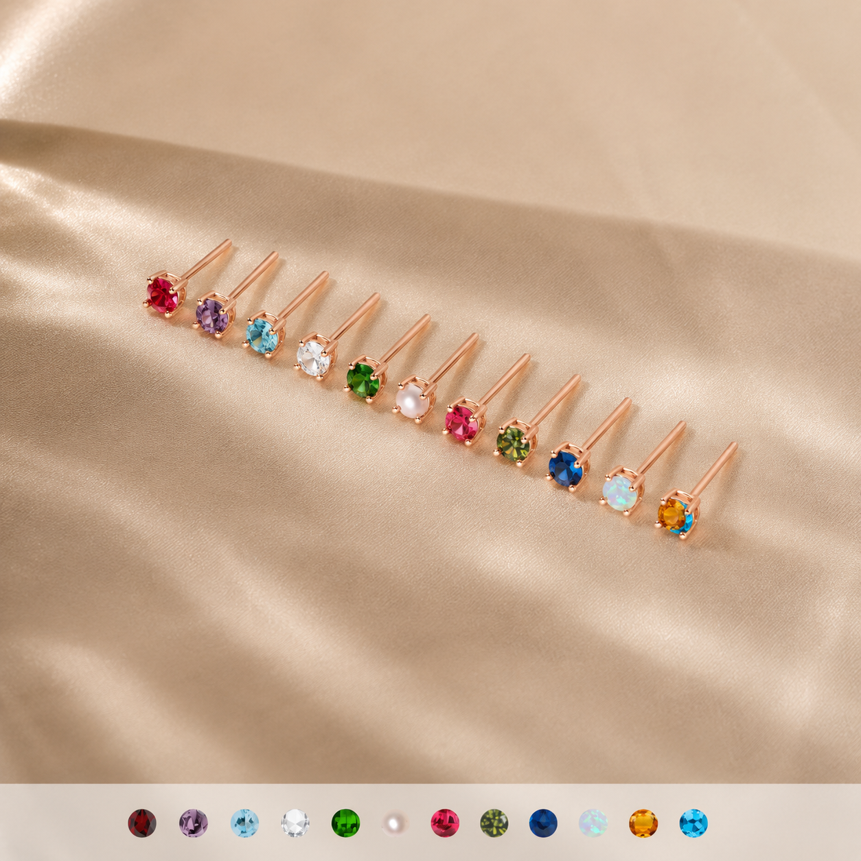 Row of rose gold earrings with multicolored gemstones on a beige fabric background
