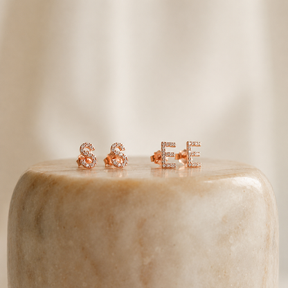 Rose gold 'S'&'E' letter earrings on a marble surface with a neutral background