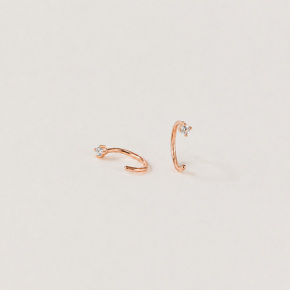Rose gold ear cuffs with small diamonds on a light gray background