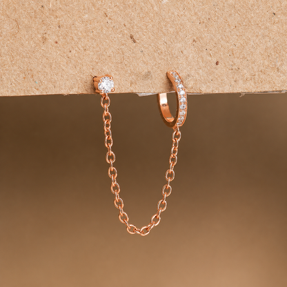 Rose gold chain earring and hoop earring on a brown background