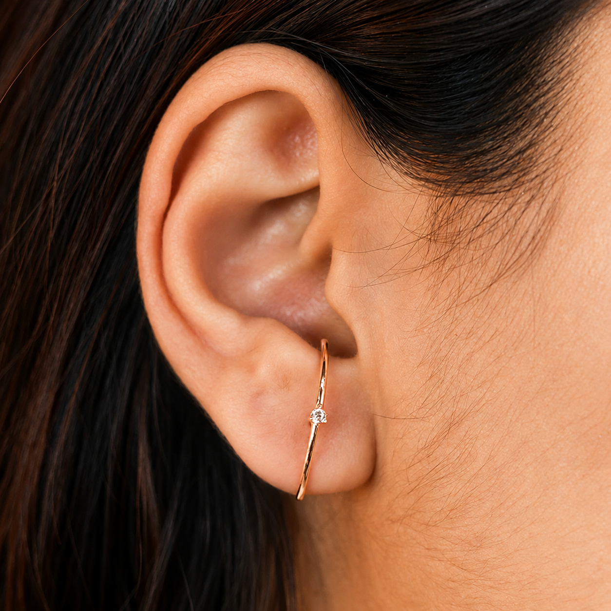 Close-up of an ear wearing a gold earring with a small gemstone.