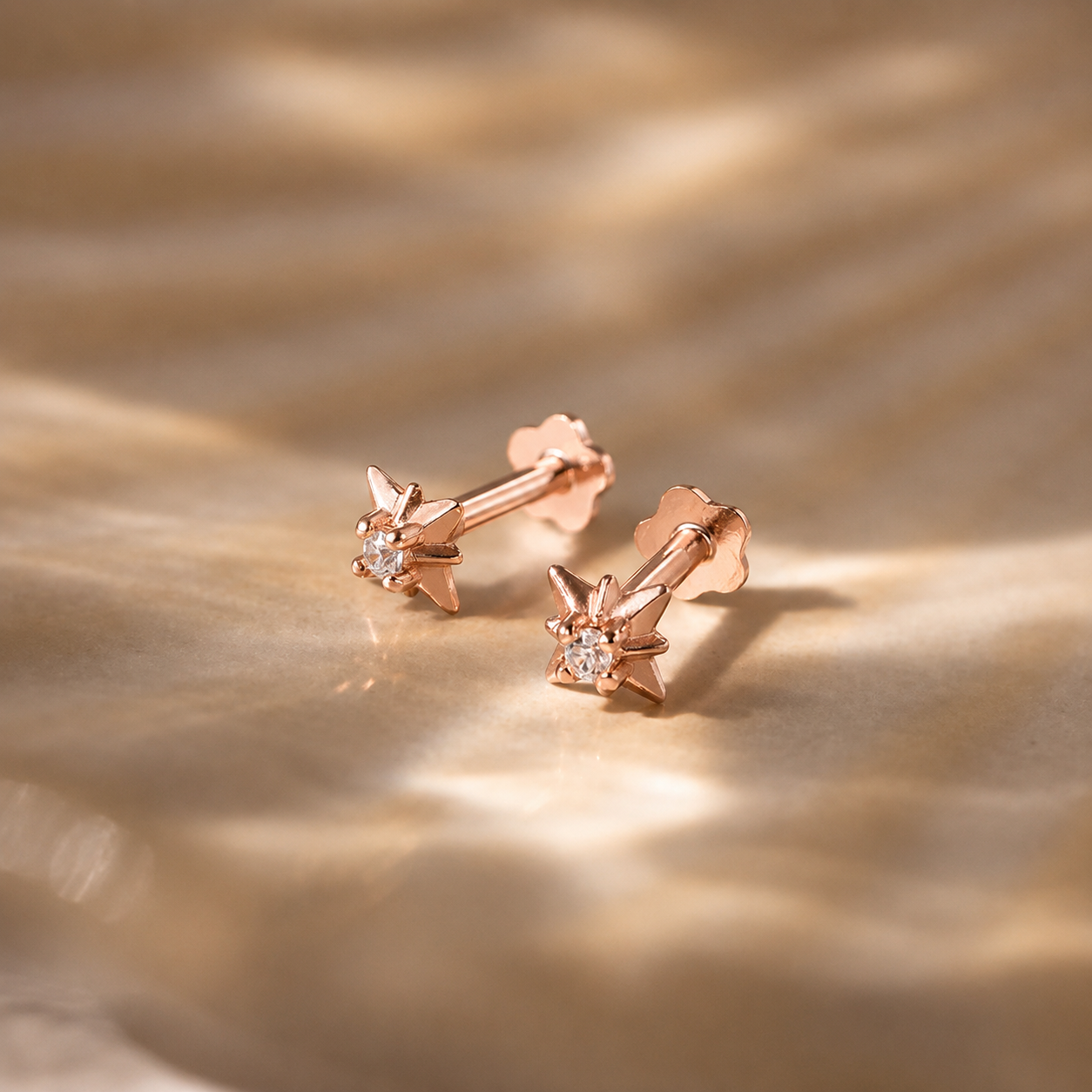 Rose gold earrings with small diamonds on a textured gold surface