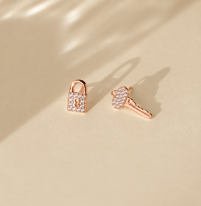 Rose gold lock-shaped earrings on a beige background