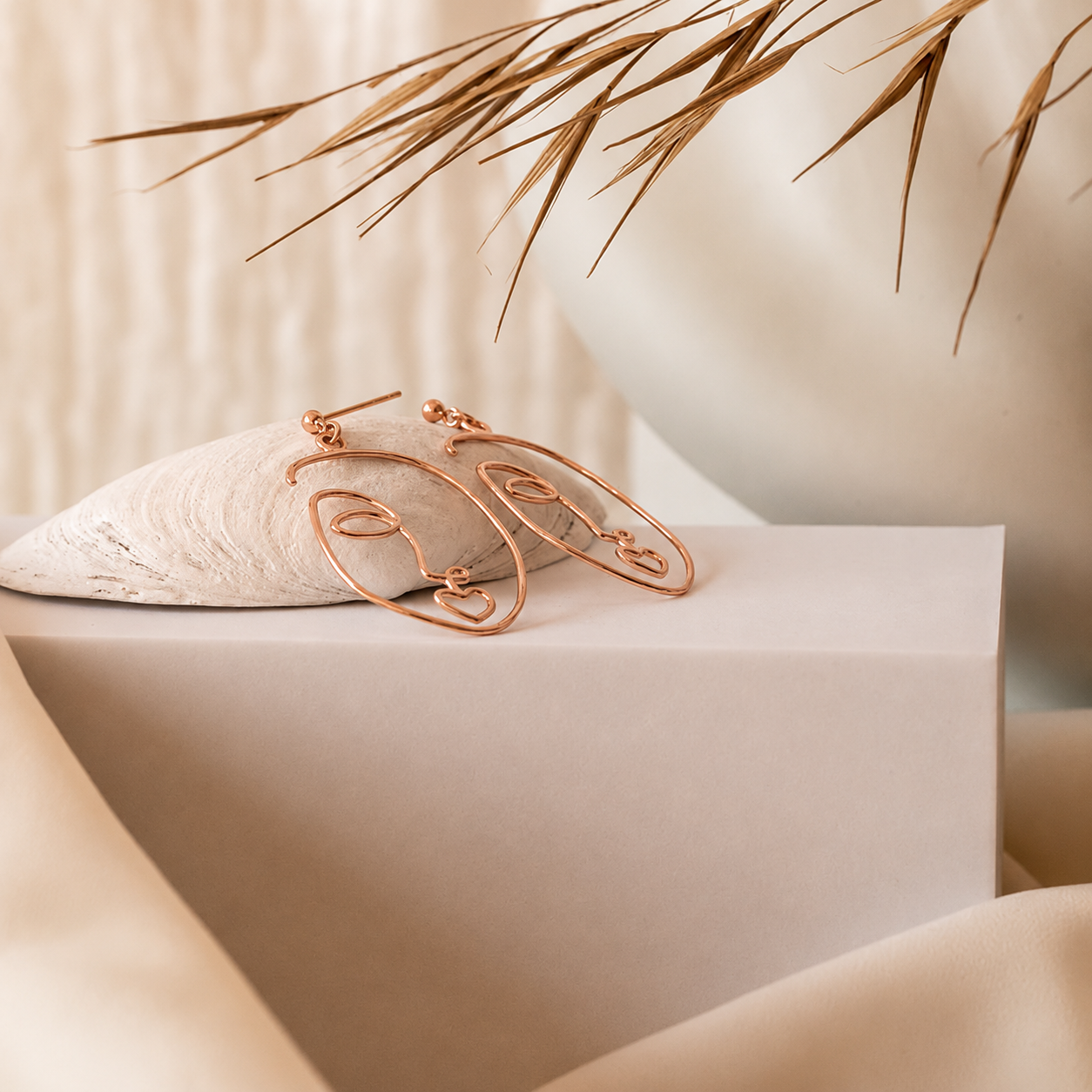 Rose gold hoop earrings on a white surface with a neutral background