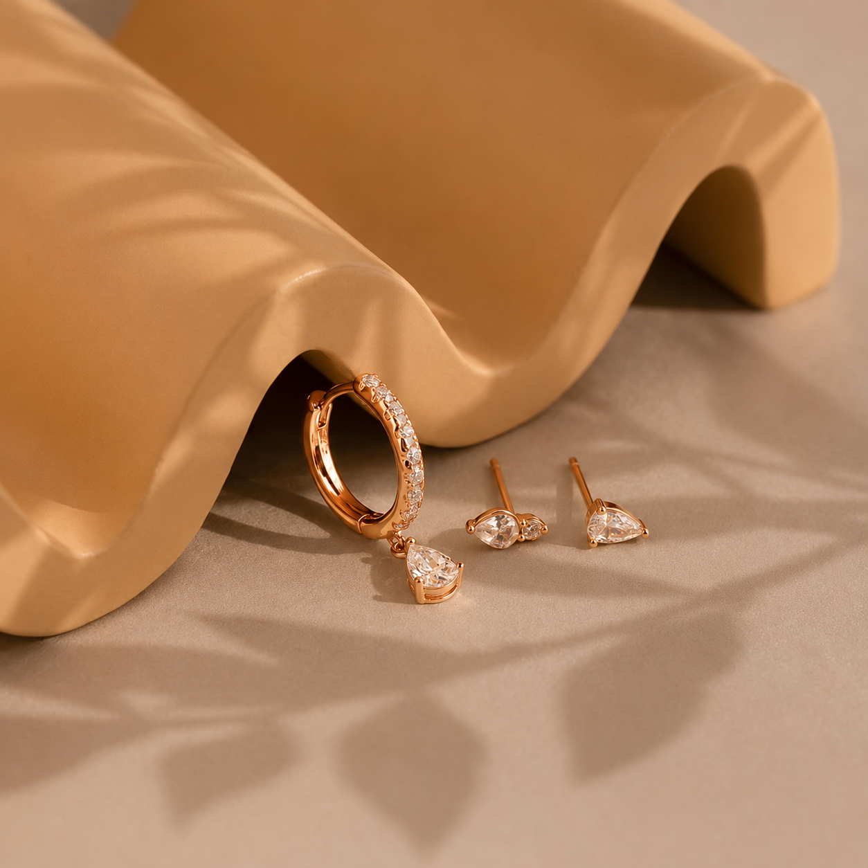 Rose gold earrings on a beige fabric background