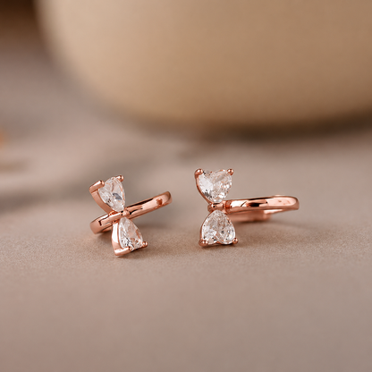 Rose gold earrings with clear gemstones on a beige background