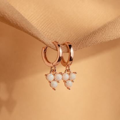 Rose gold hoop earrings with pearl drops on a beige fabric background