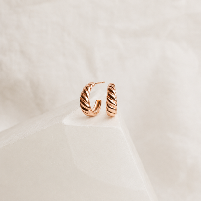 Rose gold hoop earrings on a light beige background