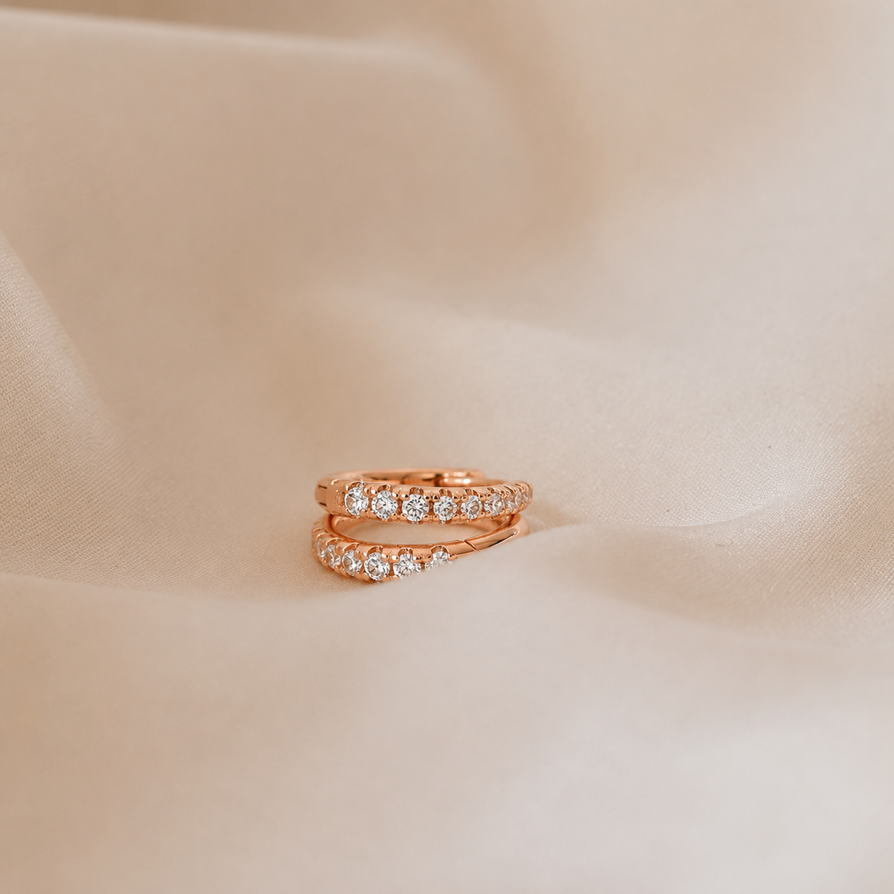 Rose gold ring with diamonds on a beige fabric background