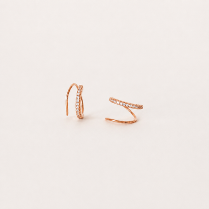 Rose gold hoop earrings on a light beige background