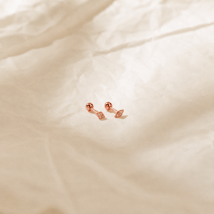 Rose gold earrings on a soft beige fabric background