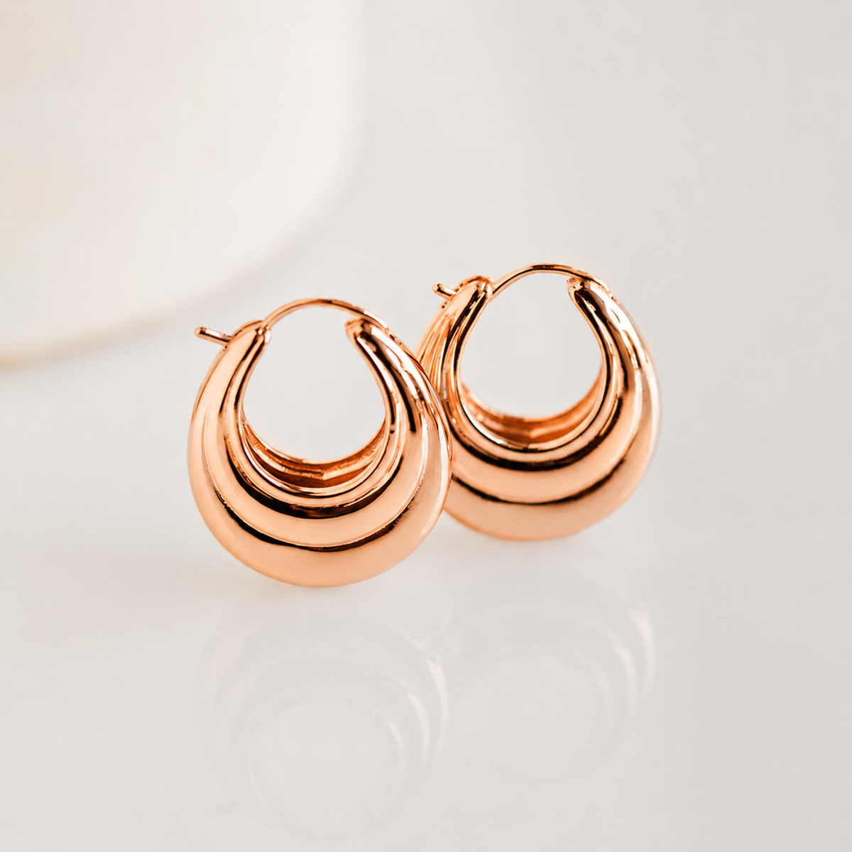 Rose gold hoop earrings on a light background