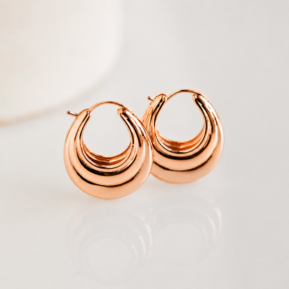 Rose gold hoop earrings on a light background