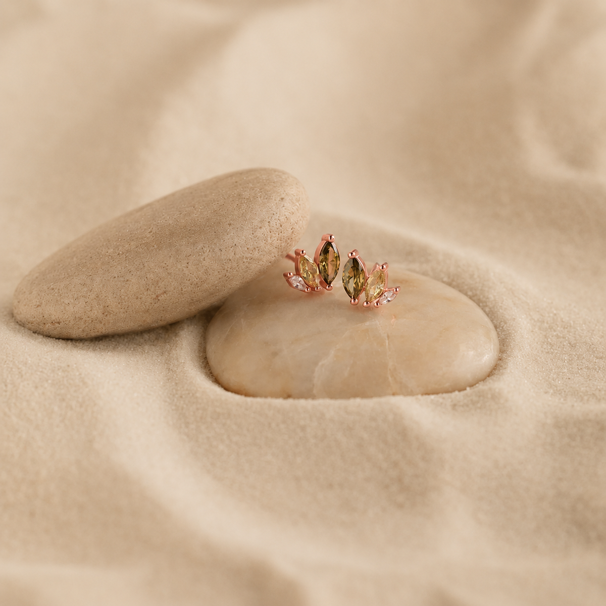 Pair of earrings on a stone with sand background