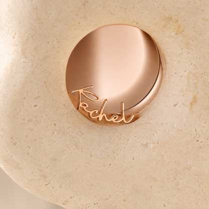 Rose gold compact with 'Trish McEvoy' branding on a beige stone background