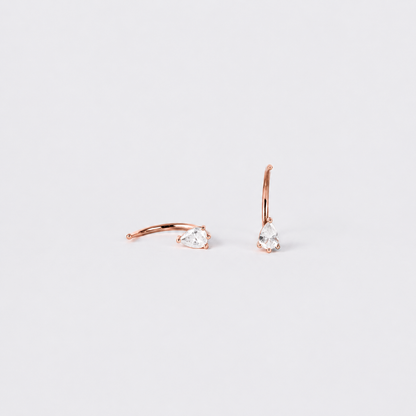 Rose gold hoop earrings with clear gemstones on a light gray background