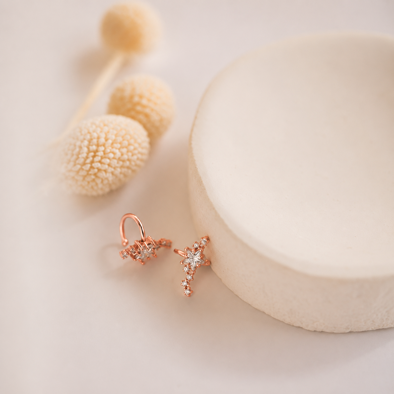 Rose gold earrings with a small diamond on a light background